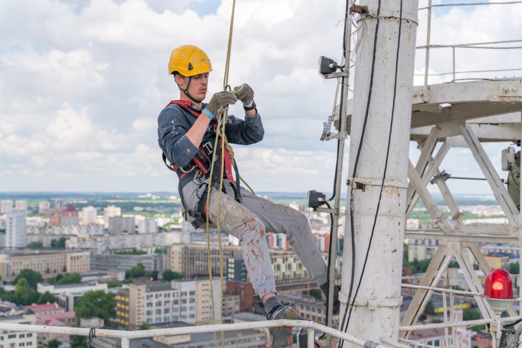 a worker climbing a tower to install equipment