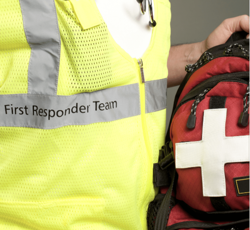 closeup of first responder yellow vest carrying first aid backpack